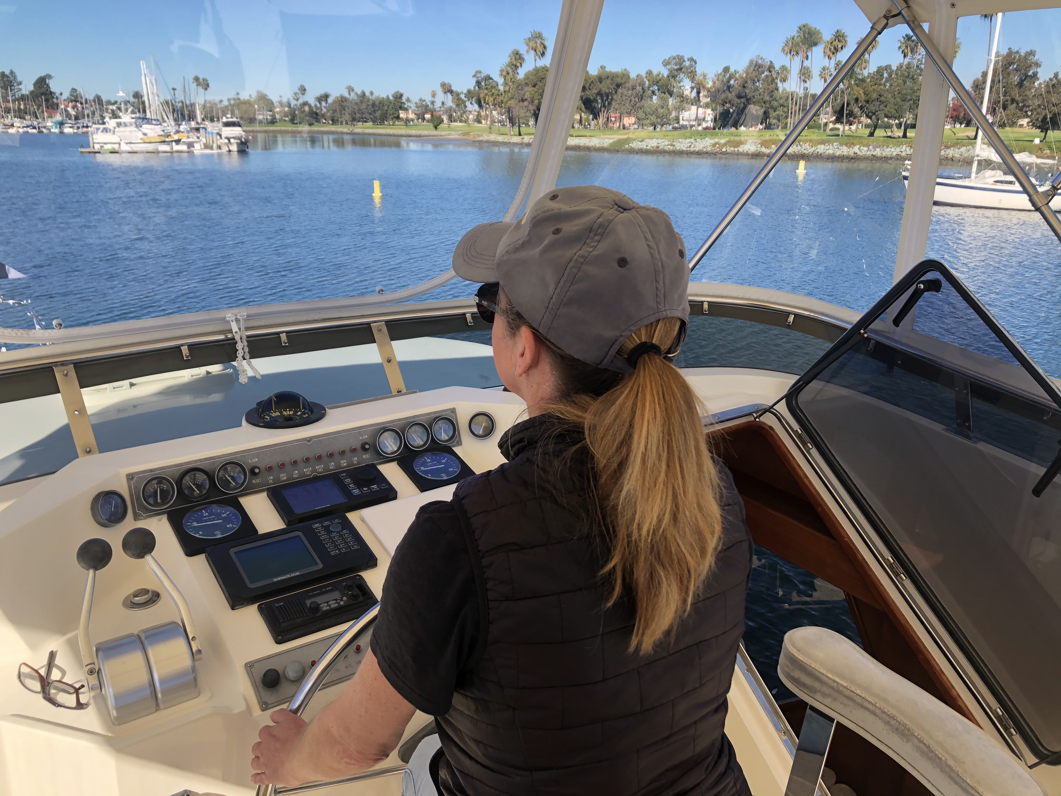 Woman at the steering wheel, learning how to captain her own boat with the help of instructors.